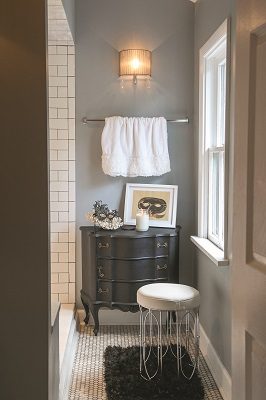 The guest bath features a quietly-classic turn with a subway tile steam shower, honeycomb floor tile, soothing blue-hued walls and original artwork by Abraham Renko. 
