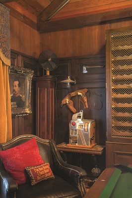 Displaying an impressive collection of curiosities, including a suit of armor, old slot machine and cowboy holster, the billiard room’s dark paneling and vaulted ceiling are a dramatic backdrop to a vintage canoe turned chandelier hung over the pool table. 