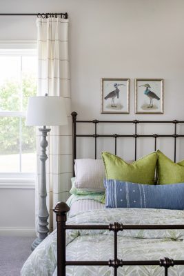 A neutral palette, combined with a classic wrought-iron bed and vintage ornithological prints, bring a classic vibe to the guest suite.