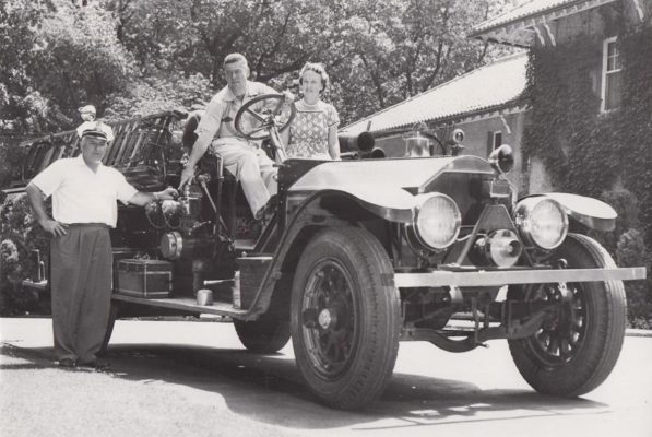 George F. Getz, Jr., stands in the Edgewood driveway beside a vintage fire truck that comprised part of his extensive collection of antique and vintage firefighting equipment. The collection was originally displayed
in an outbuilding on the Edgewood property, but it soon outgrew the space. Today, Getz’s collection makes up the bulk of the exhibits at the Hall of Flame Museum in Phoenix, Arizona.  Photo courtesy of Geneva Lake Museum