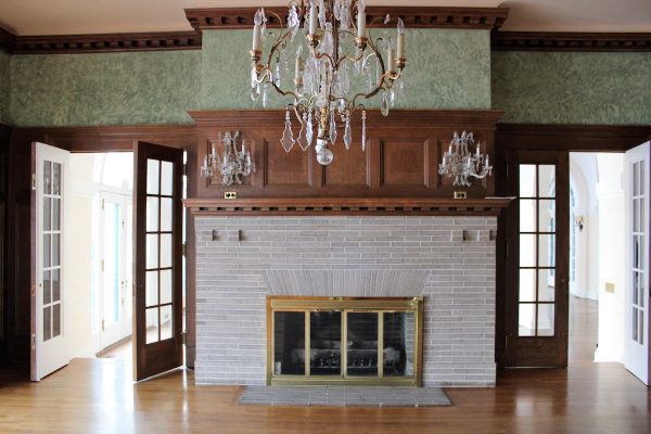 The wood-paneled main dining room featured a large brick fireplace, a crystal chandelier and sconces, as well as French doors leading to the Great Hall.  Photo courtesy of Geneva Lake Museum