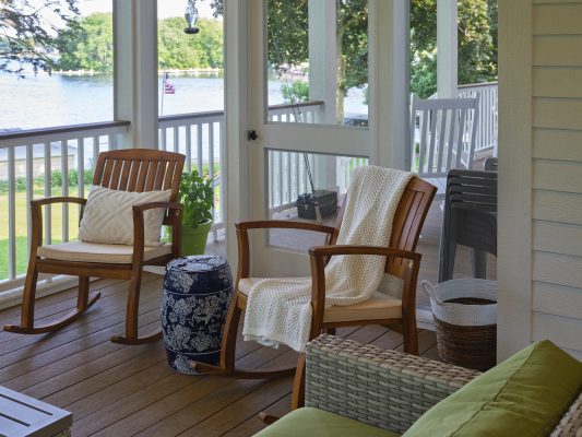 Natural wood rocking chairs on the screened porch complement white rocking chairs on the open porch, all of which allow for comfortable viewing of the home’s spectacular lake views.