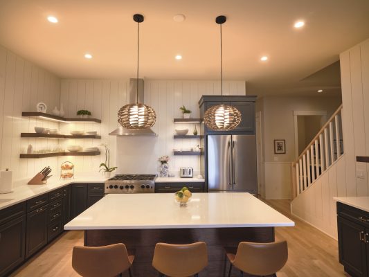 The large kitchen island is perfect for preparing meals for the many friends and family members who visit. Bentwood pendant lights and leather-covered stools lend a modern touch to the traditional kitchen design. 
