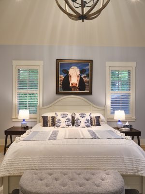 A striking painting over the bed in the primary suite lends personality to the space, while plantation shutters continue the southern design theme that runs throughout the home.