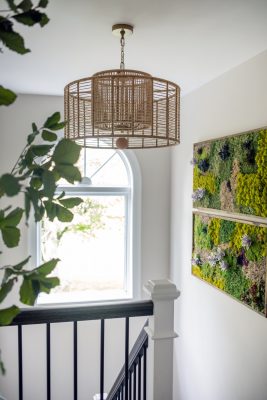 A hanging rattan
pendant by Crystorama and succulent wall panels add character to the entry stairs.