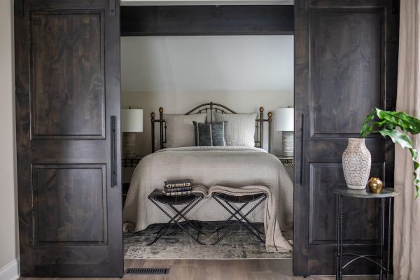 Wooden barn doors finished in a dark gray stain provide privacy to the primary bedroom.