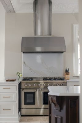 The 48-inch stove is anchored by a dramatic hood and marble backsplash.